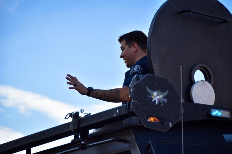 A police officer waves to the crowd from the top hatch of a Police response vehicle during the annual Halloween Parade.