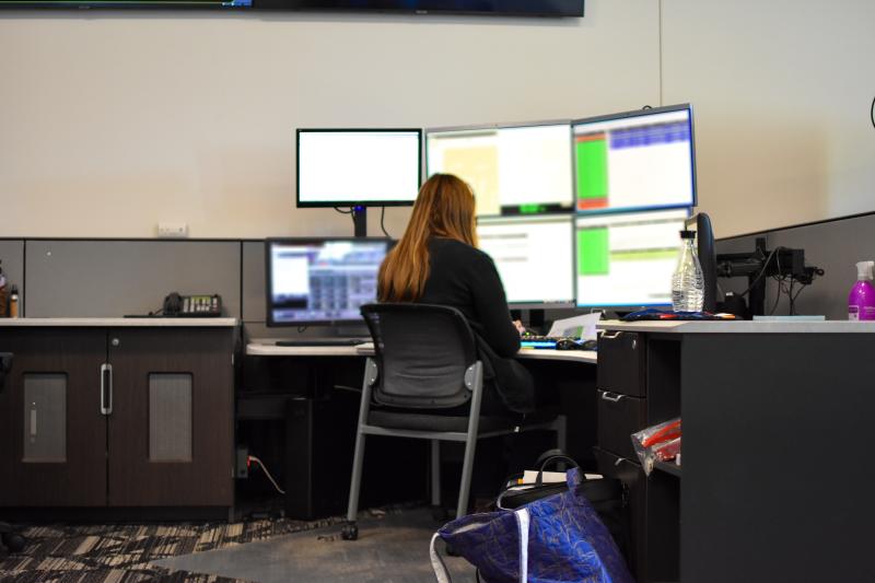 A 9-1-1 dispatcher sits in front of a computer with multiple screens. 